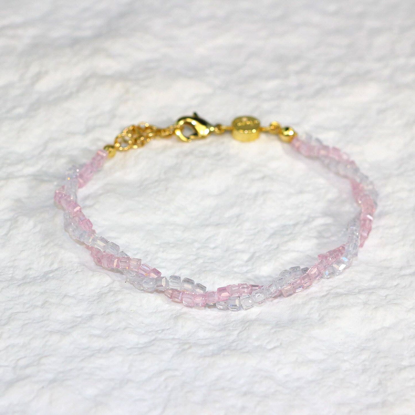 A close-up of the Blush Prism Bracelet, showcasing warm champagne-pink crystal beads with a luminous finish. The stretch bracelet features a sparkling CZ accent bead, styled on a woman’s wrist with soft natural lighting for an elegant, feminine look.