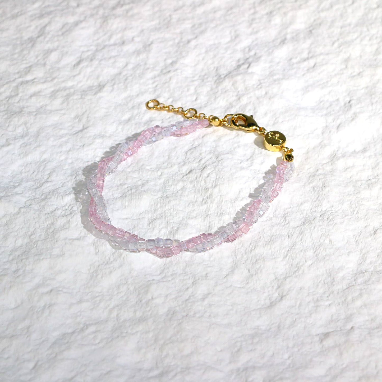 A close-up of the Blush Prism Bracelet, showcasing warm champagne-pink crystal beads with a luminous finish. The stretch bracelet features a sparkling CZ accent bead, styled on a woman’s wrist with soft natural lighting for an elegant, feminine look.