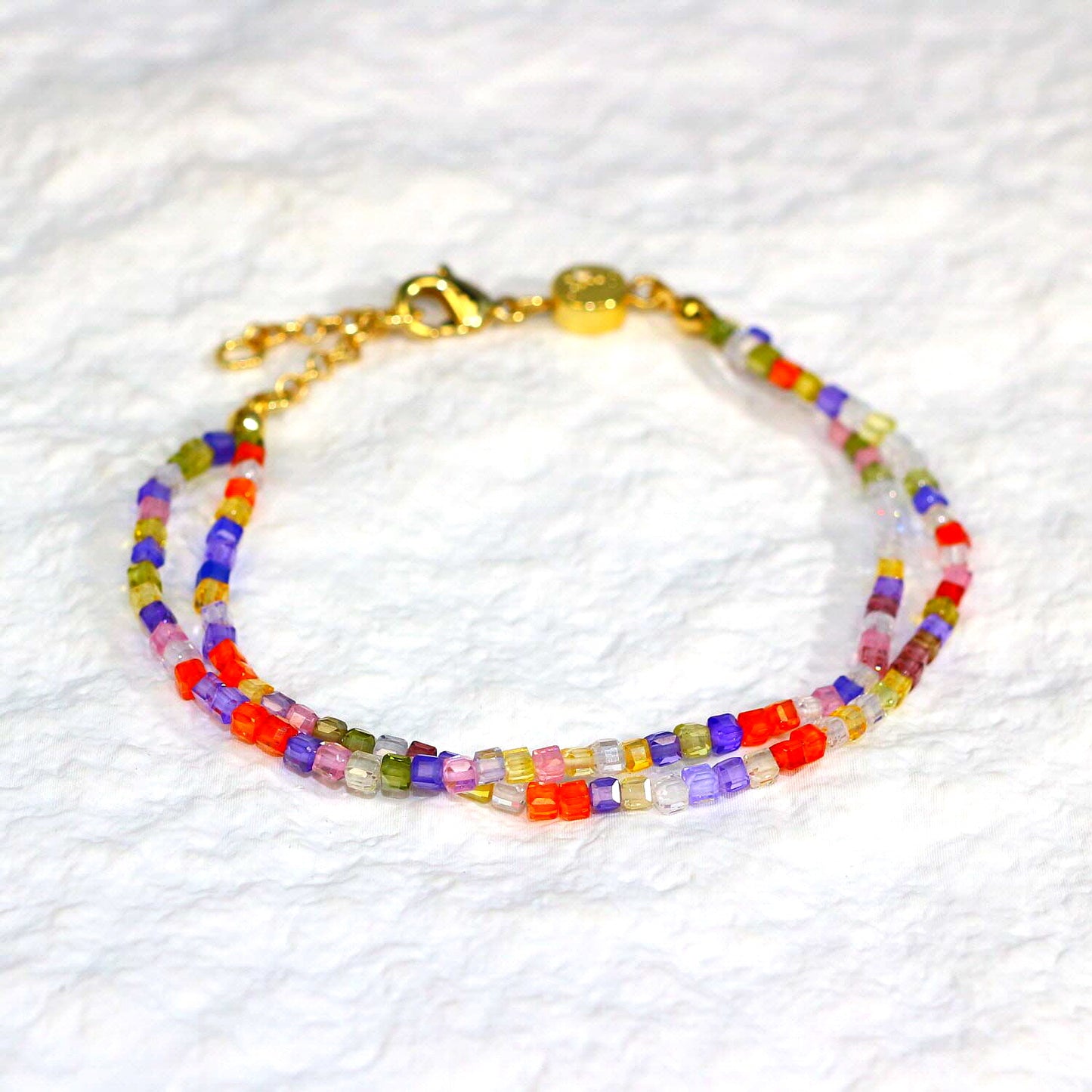 A close-up of the Joy Prism Bracelet featuring soft blush-toned crystal beads with a subtle iridescent sheen. The bracelet is stretch-fit and accented with a delicate CZ bead, styled elegantly on a woman's wrist in natural sunlight.