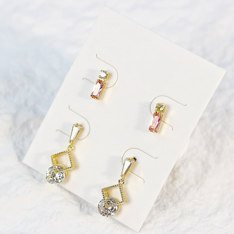 Flat lay of Dewlight Earring Set on ivory surface, showing freshwater pearl accents and delicate gold metal finish.