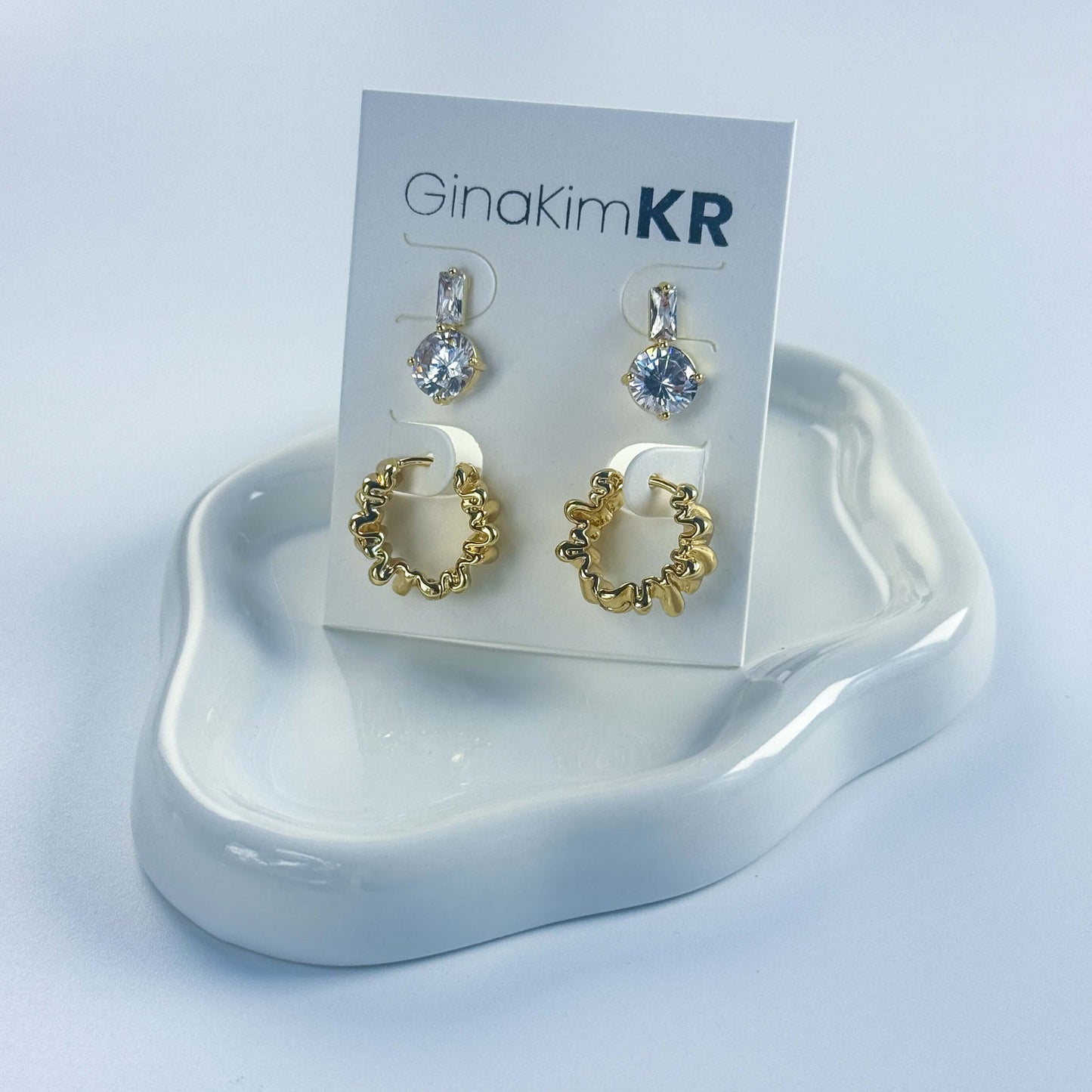 The Gleam Ripple Earrings elegantly presented on a satin cushion, emphasizing their refined and luxurious charm.
