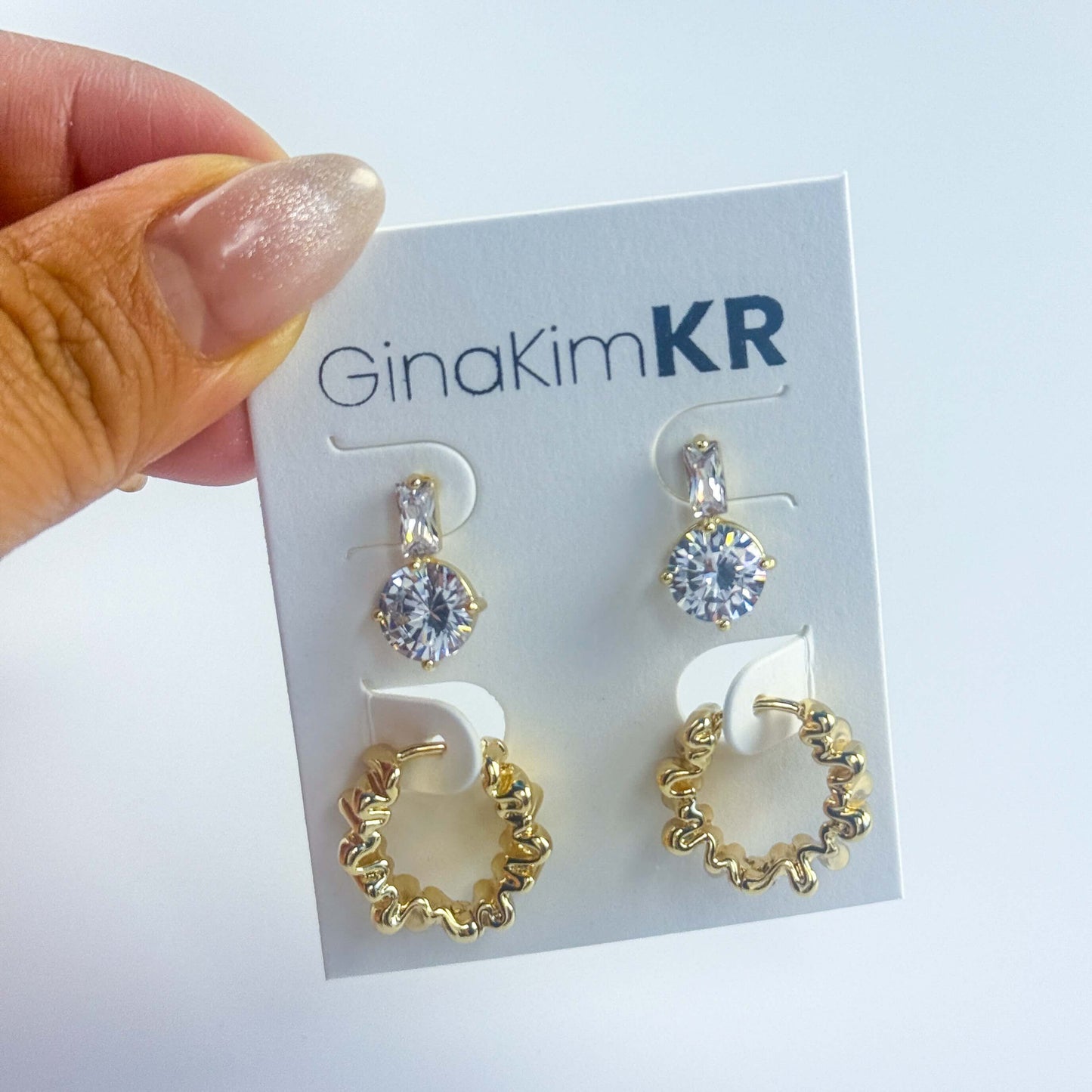 Handheld image of Gleam Ripple Earring Set on brand card, showcasing the scale and shine of this elegant accessory.