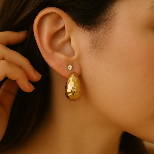 GinaKimKR Golden Radiance hammered gold drop earring worn on an ear. Showcases the lustrous gold tone and unique textured design for an elegant look