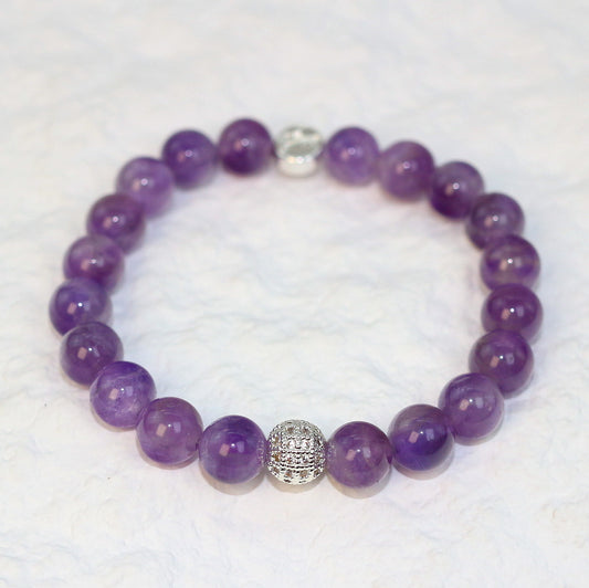 Flat-lay image of the Amethyst Strength Bracelet with glossy purple stones symbolizing calmness and intuition, designed for unisex everyday wear.