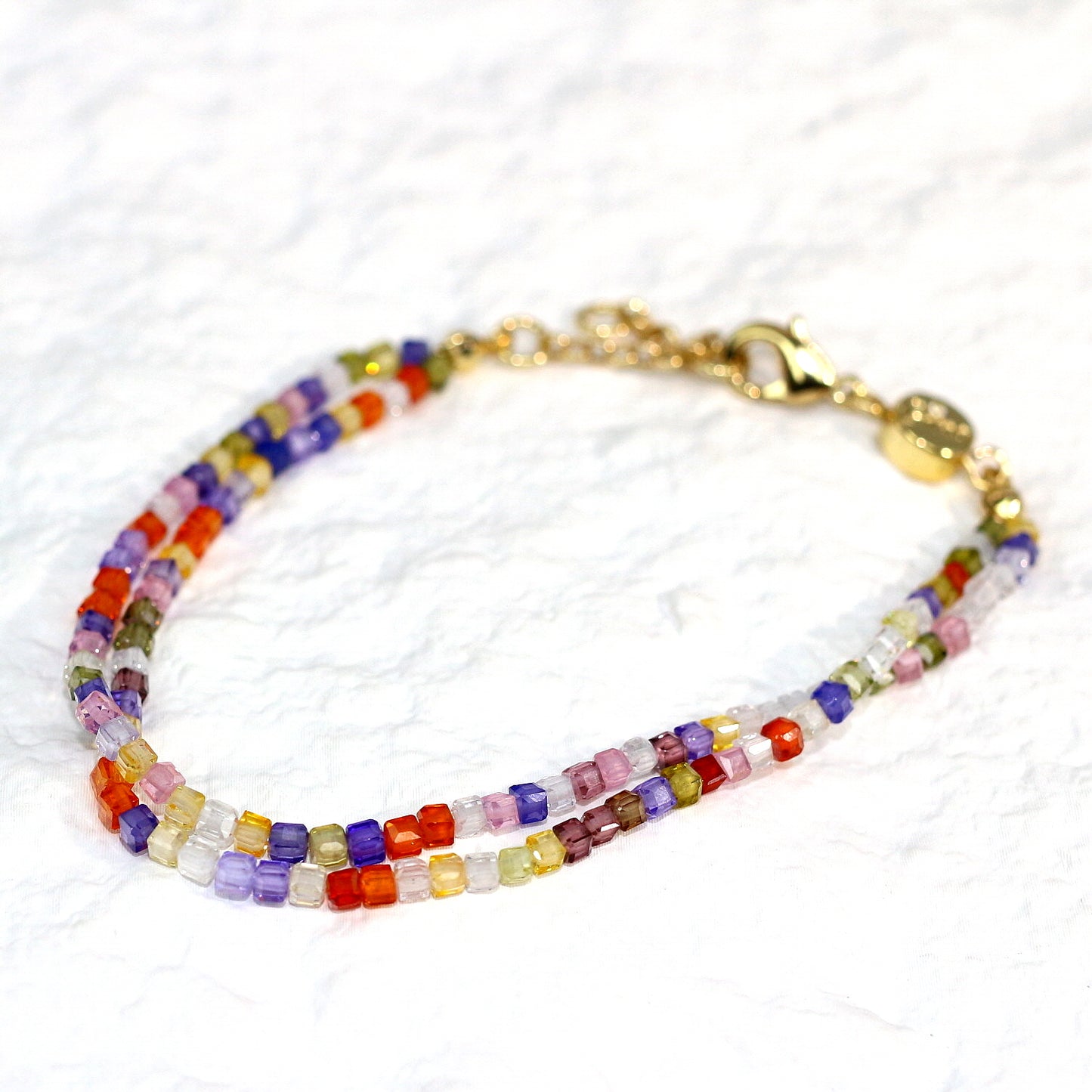 A close-up of the Joy Prism Bracelet featuring soft blush-toned crystal beads with a subtle iridescent sheen. The bracelet is stretch-fit and accented with a delicate CZ bead, styled elegantly on a woman's wrist in natural sunlight.