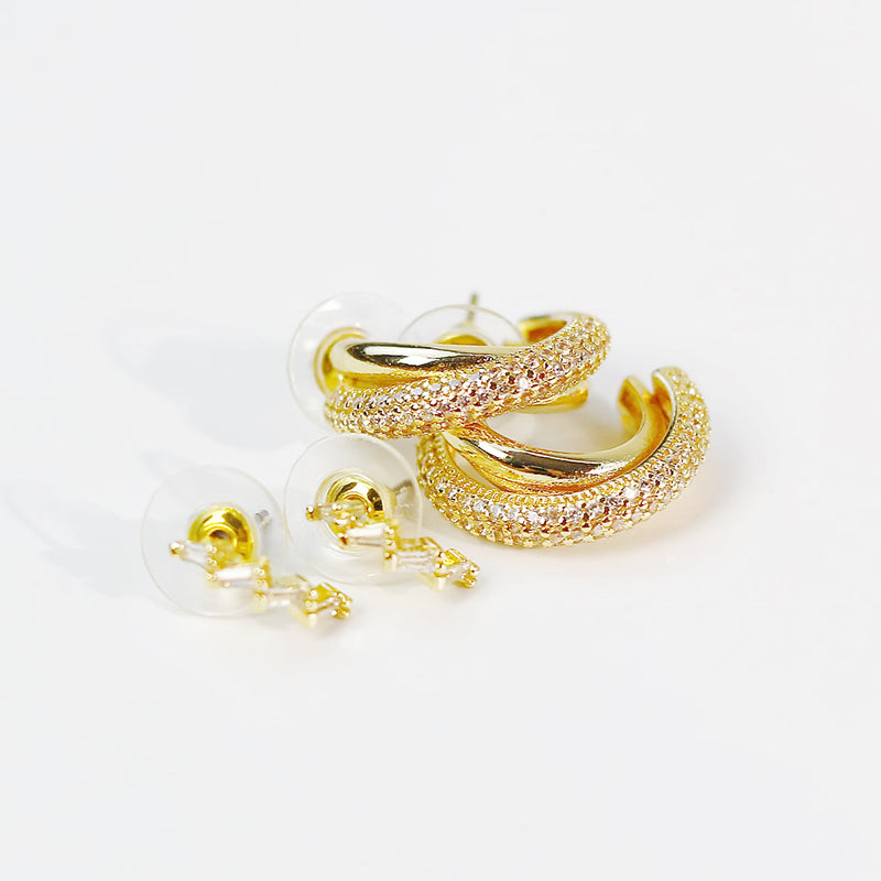 Scattered display of GinaKimKR Luna Curve gold earrings set on light surface, capturing elegant curved silhouettes.