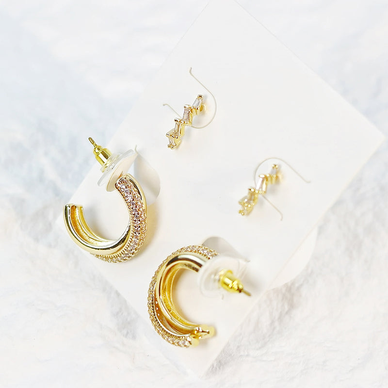 Dynamic top view of Luna Curve gold earrings scattered across white surface, highlighting modern crescent shapes.