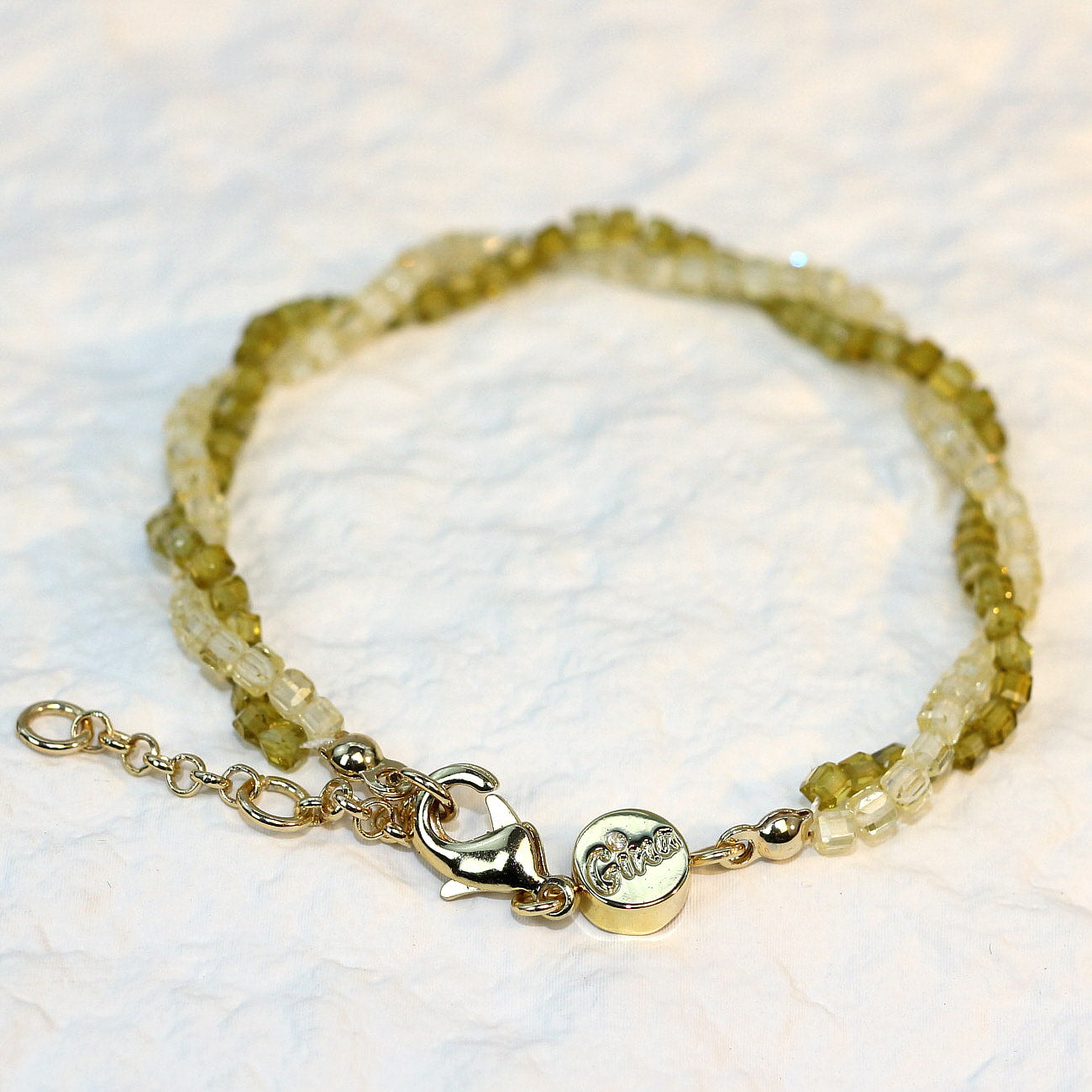 A close-up of the Olive Prism Bracelet featuring soft olive green crystal beads with a subtle shimmer. The bracelet is stretch-fit and accented with a sparkling CZ bead, worn on a woman's wrist in warm natural sunlight for a calm and elegant look.