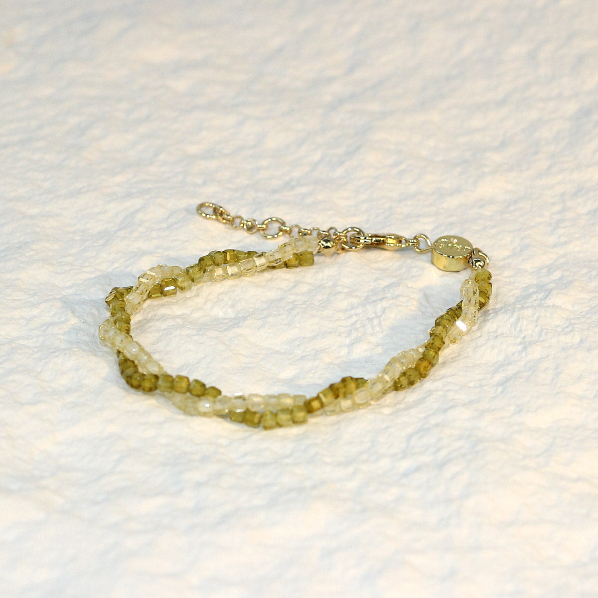 A close-up of the Olive Prism Bracelet featuring soft olive green crystal beads with a subtle shimmer. The bracelet is stretch-fit and accented with a sparkling CZ bead, worn on a woman's wrist in warm natural sunlight for a calm and elegant look.