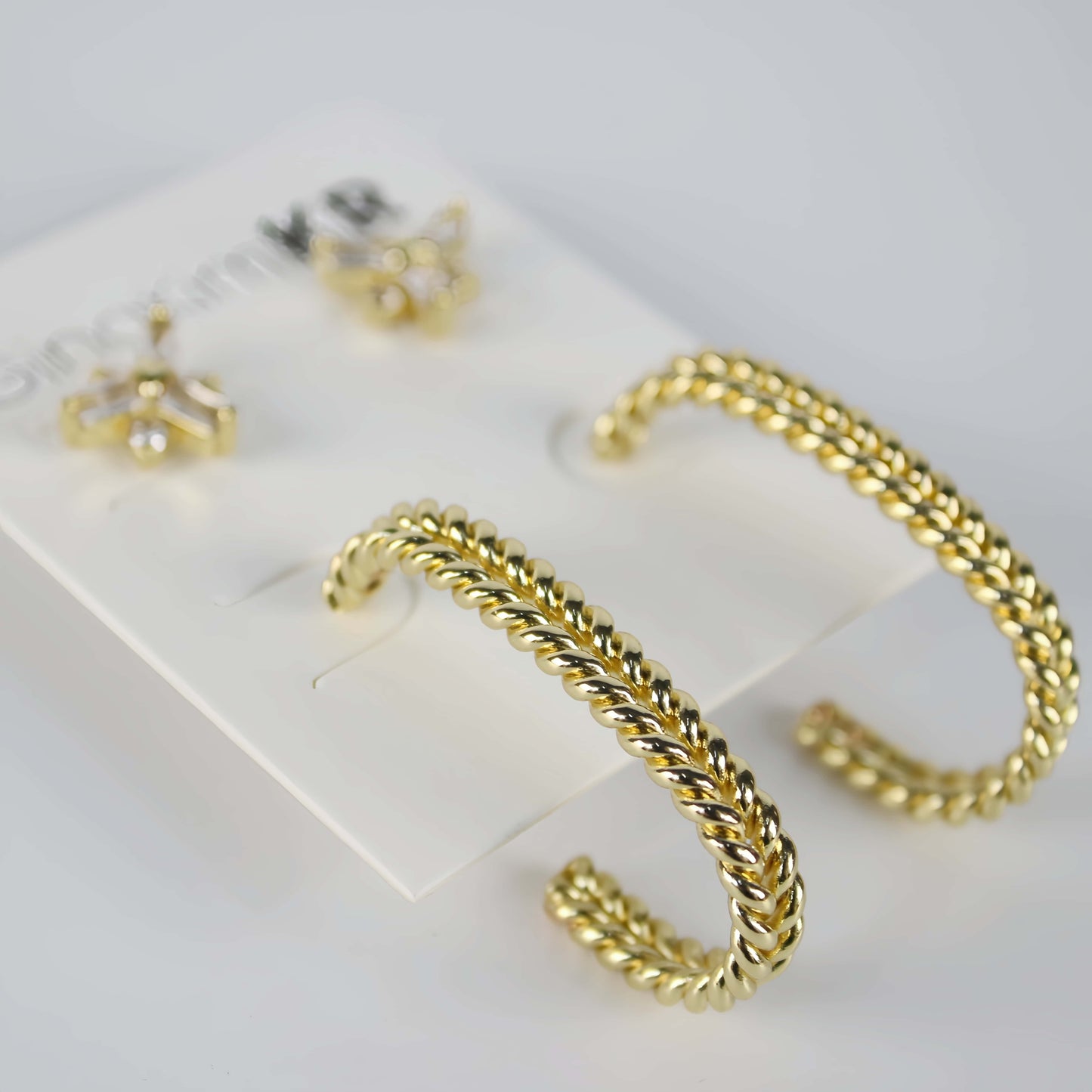 Side view of gold twist hoop earrings and CZ floral studs on GinaKimKR card – Twist Bloom Earring Set