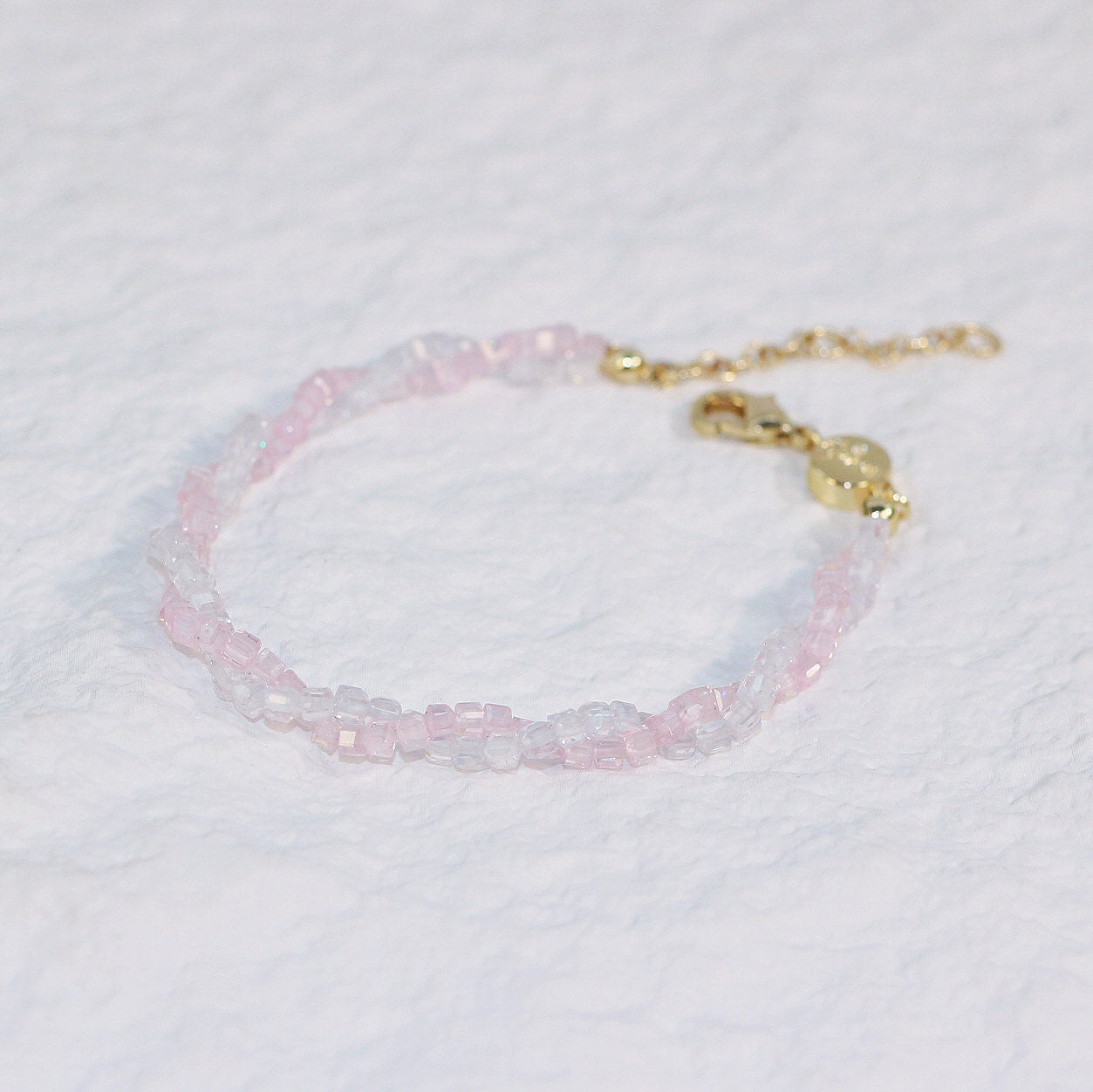 Close-up of the Blush Prism Bracelet with delicate pink and clear CZ beads, finished with a gold clasp and extension chain on white background.