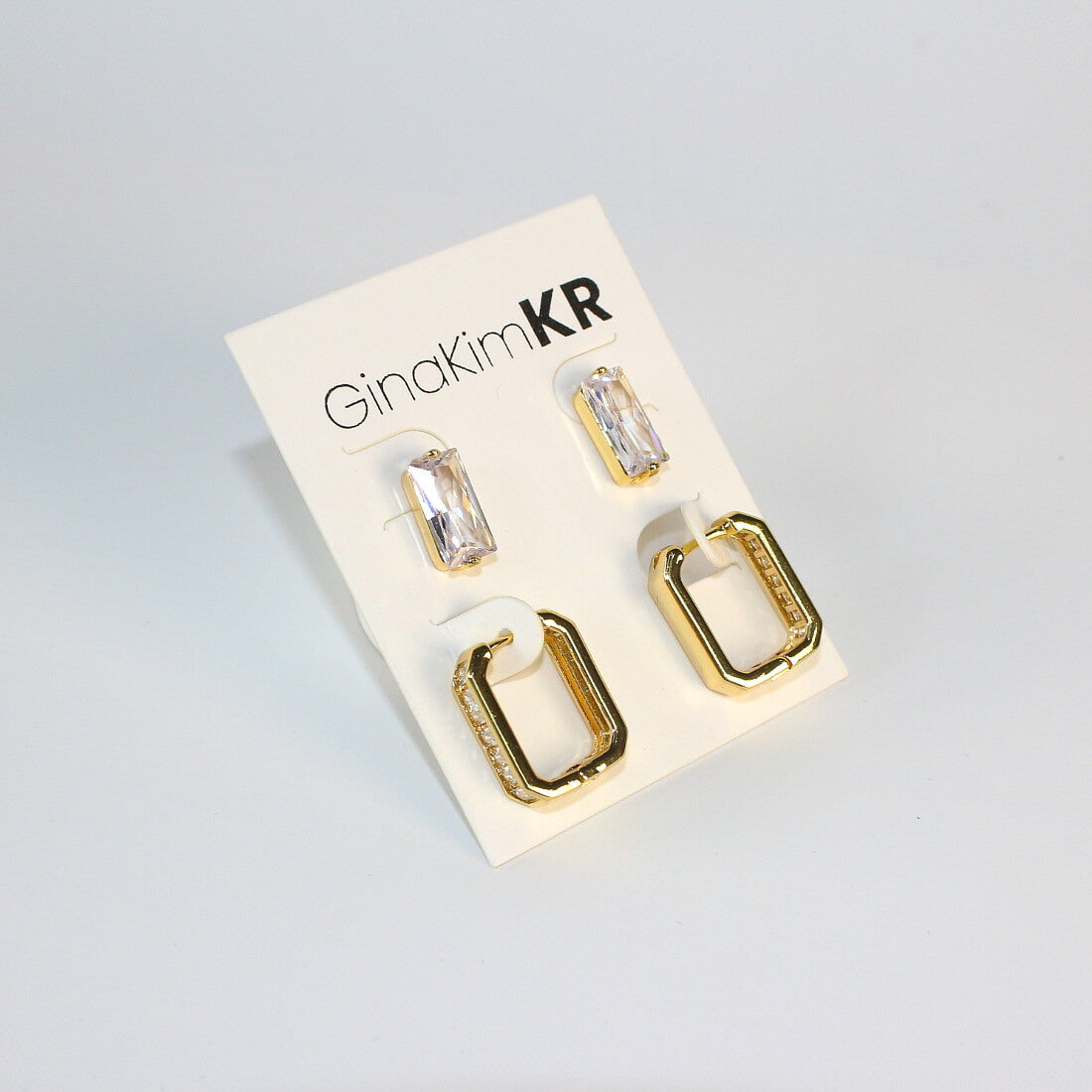 Front-facing view of Crystal Line Duo earring set by GinaKimKR – rectangular CZ studs and baguette hoops on white card