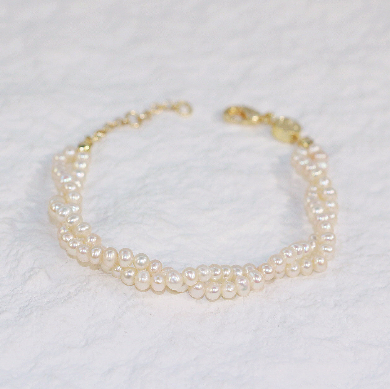 Flat-lay view of Double Grace Pearl Bracelet, highlighting the soft glow of freshwater pearls and sophisticated double-layer design on a neutral background.