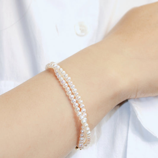 GinaKim Double Grace Pearl Bracelet on wrist, showing double strands of elegant pearls and gold hardware—ideal for formal looks or special occasions.
