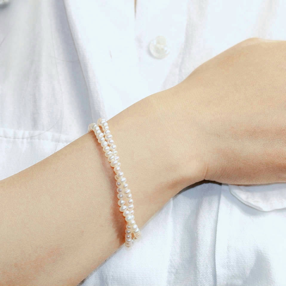 GinaKim Double Grace Pearl Bracelet on wrist, featuring two strands of lustrous freshwater pearls, creating an elegant and timeless look. Perfect for sophisticated style and special occasions.