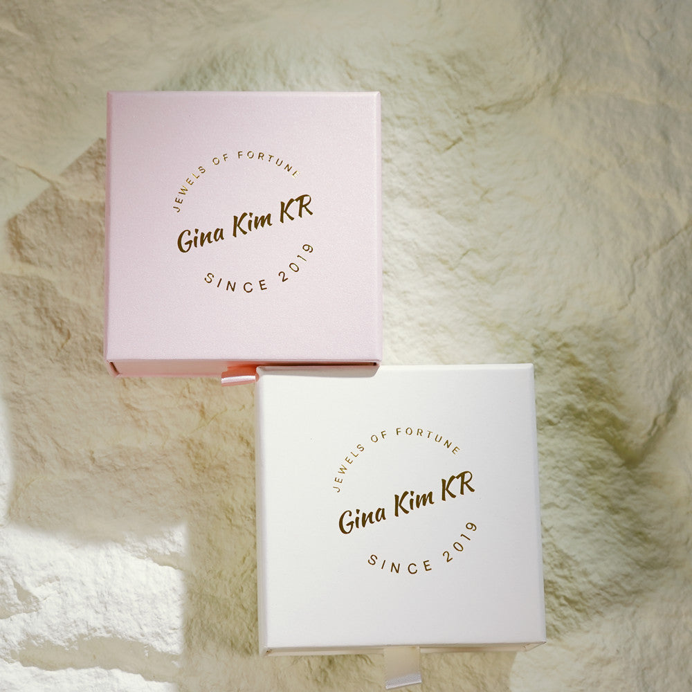 GinaKimKR signature jewelry gift boxes in pastel pink and white. Two sliding-drawer boxes are layered on a raw natural stone background. The gold foil logo "Jewels of Fortune, Gina Kim KR, SINCE 2019" is stamped in the center, showcasing a luxurious packaging for special gifts.