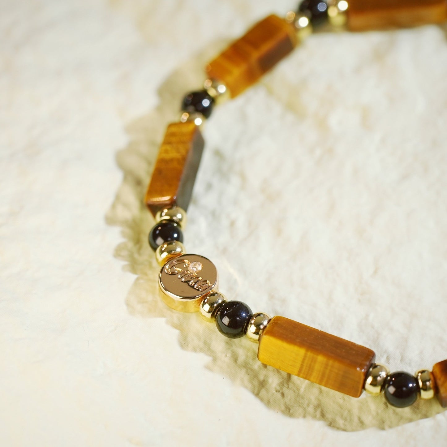 GinaKim Focus Strength Bracelet featuring natural Tiger's Eye and Onyx beads, with gold-plated accents and a stretch design for a luxurious, empowering look