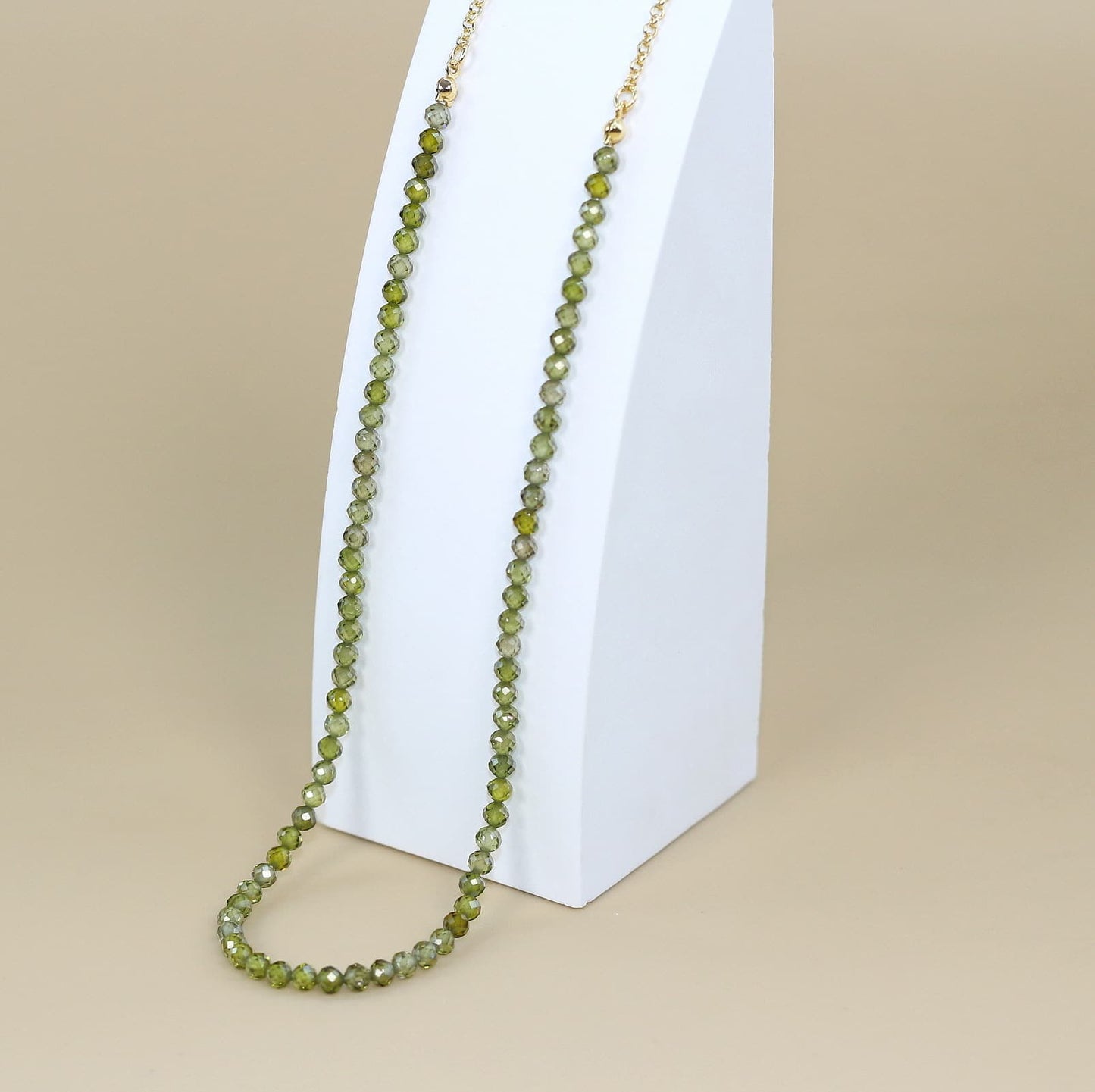 Overhead view of the Forest Light Necklace arranged in a spiral, highlighting the sparkle of faceted forest green CZ beads and warm gold-toned details.