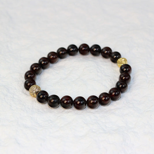 Top-down view of the Garnet Strength Bracelet featuring deep wine-red 8mm round beads arranged in a circle on a soft white background.