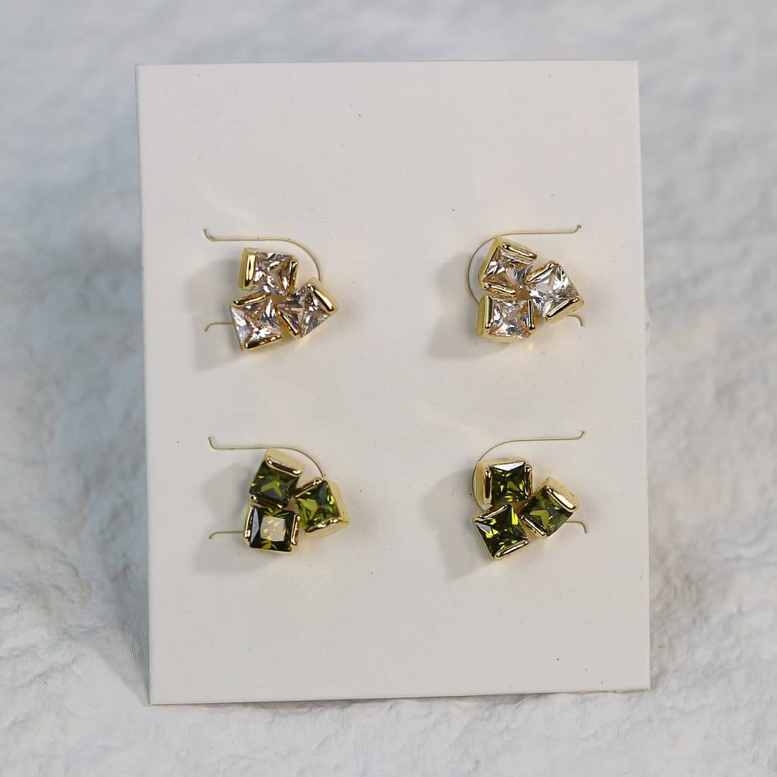Geo Trio Earrings close-up showing gold-tone finish and clustered CZ stones in light and green hues.
