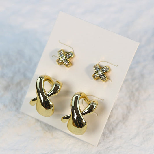 Eternal Flow Earring Set displayed on a white card, featuring one pair of sculptural gold-tone earrings and one pair of 9.6mm crisscross CZ studs.