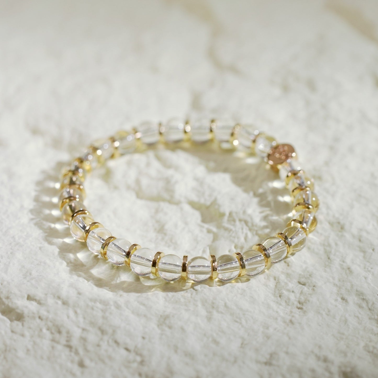 A crystal quartz stretch bracelet with gold-toned spacers. Designed by GinaKimKR to express clarity and refined elegance.