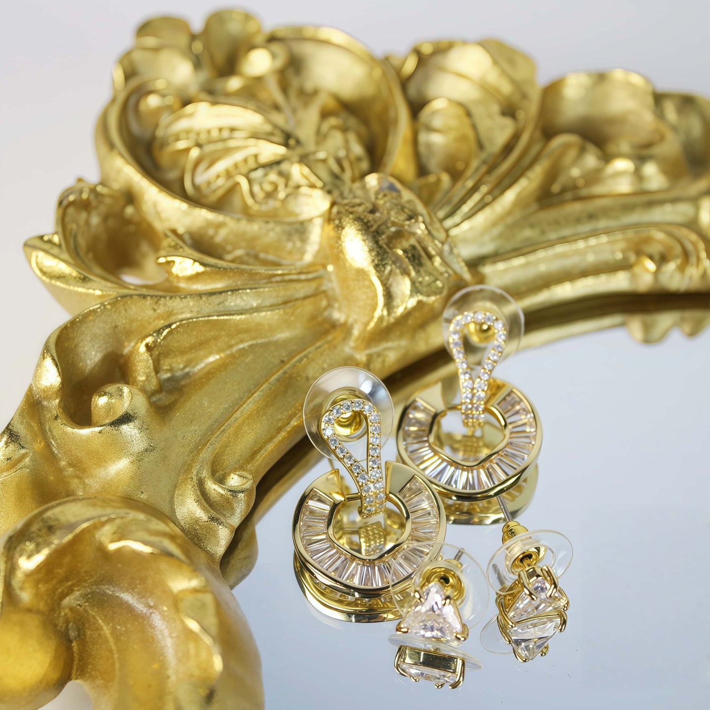 Golden Edge Duo earrings styled on vintage gold frame – triangle CZ and baguette crystal loops