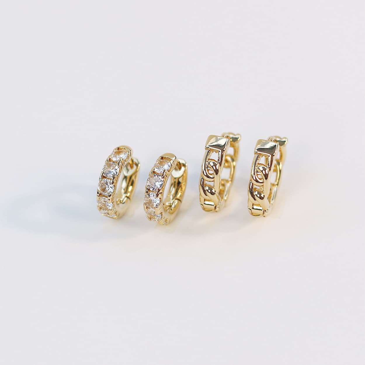 Top-down product image showing Golden Gleam Huggie Set with mixed-style gold hoops including bold, CZ-detailed, and twisted finishes.