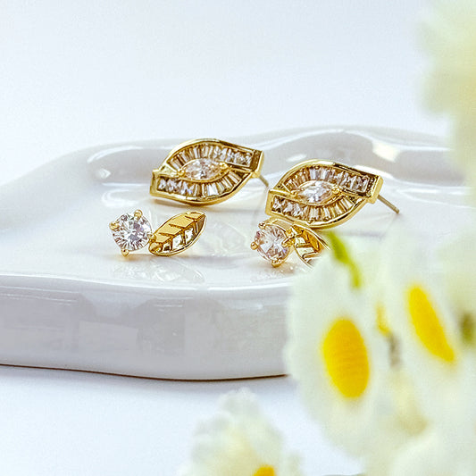 Elegant gold leaf earrings with cubic zirconia sparkle styled on a ceramic tray with floral accents, by GinaKimKR