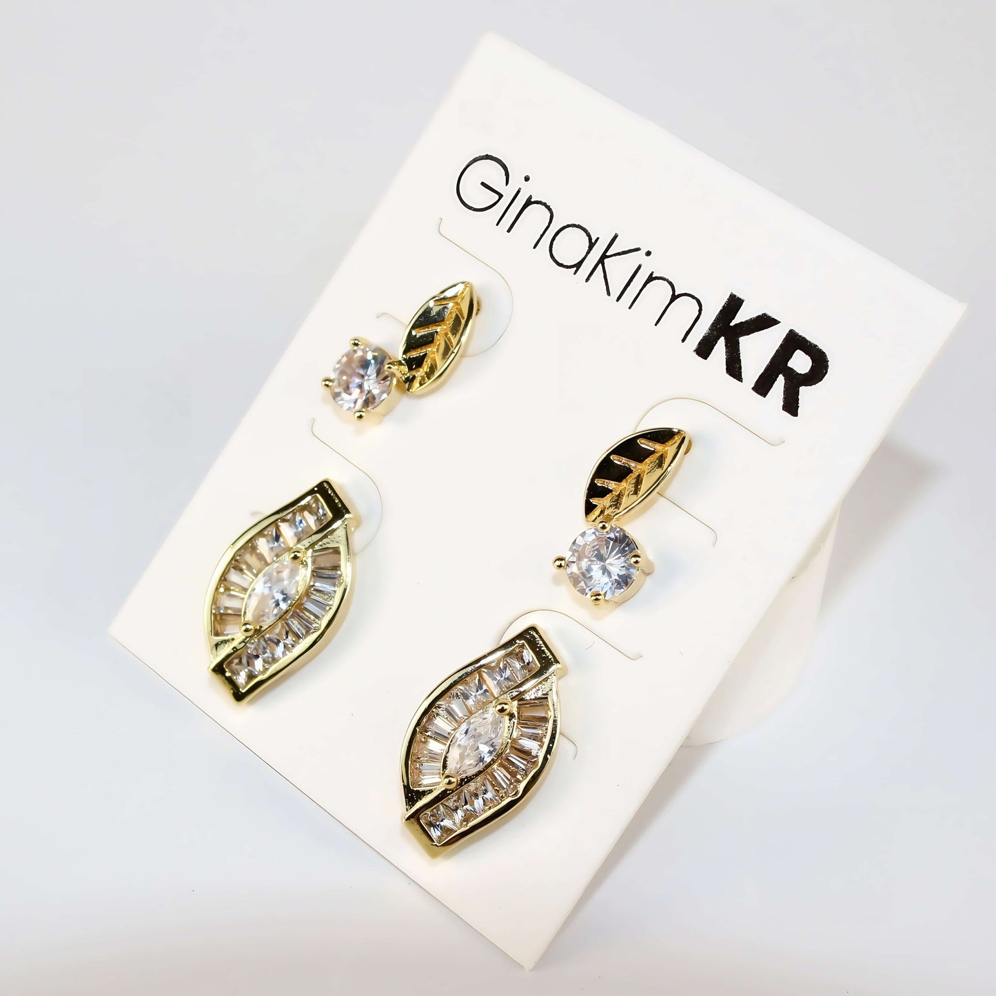 Gold-tone Harmony Leaf Trio Earrings by GinaKimKR displayed on branded card, showcasing elegant leaf and CZ design.
