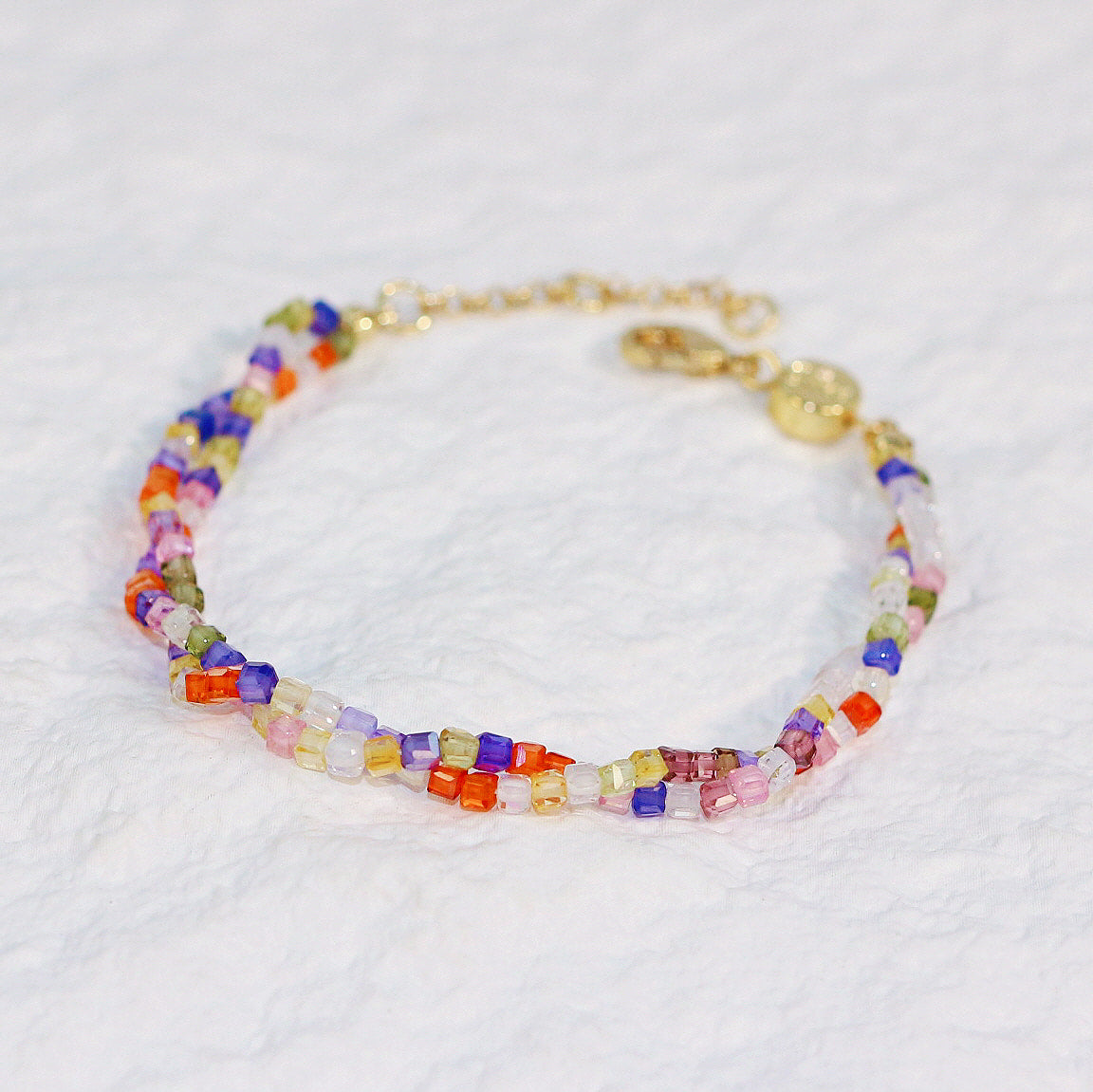 Close-up image of Joy Prism Bracelet displayed in a circular layout, showcasing colorful CZ square beads with a shell button clasp on a white background.