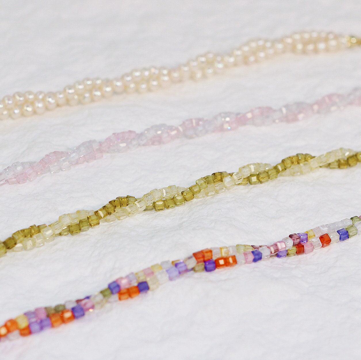 Flat-lay image of four bracelets including Joy, Olive, Blush Prism, and Double Grace Pearl, arranged side by side to highlight color variety and bead detail on a white surface.