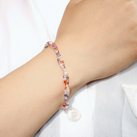 GinaKim Joy Prism Bracelet on wrist, featuring a vibrant mix of colorful cubic beads with a white shell button clasp, adding a touch of elegance and sparkle. Perfect for daily wear and casual chic style.