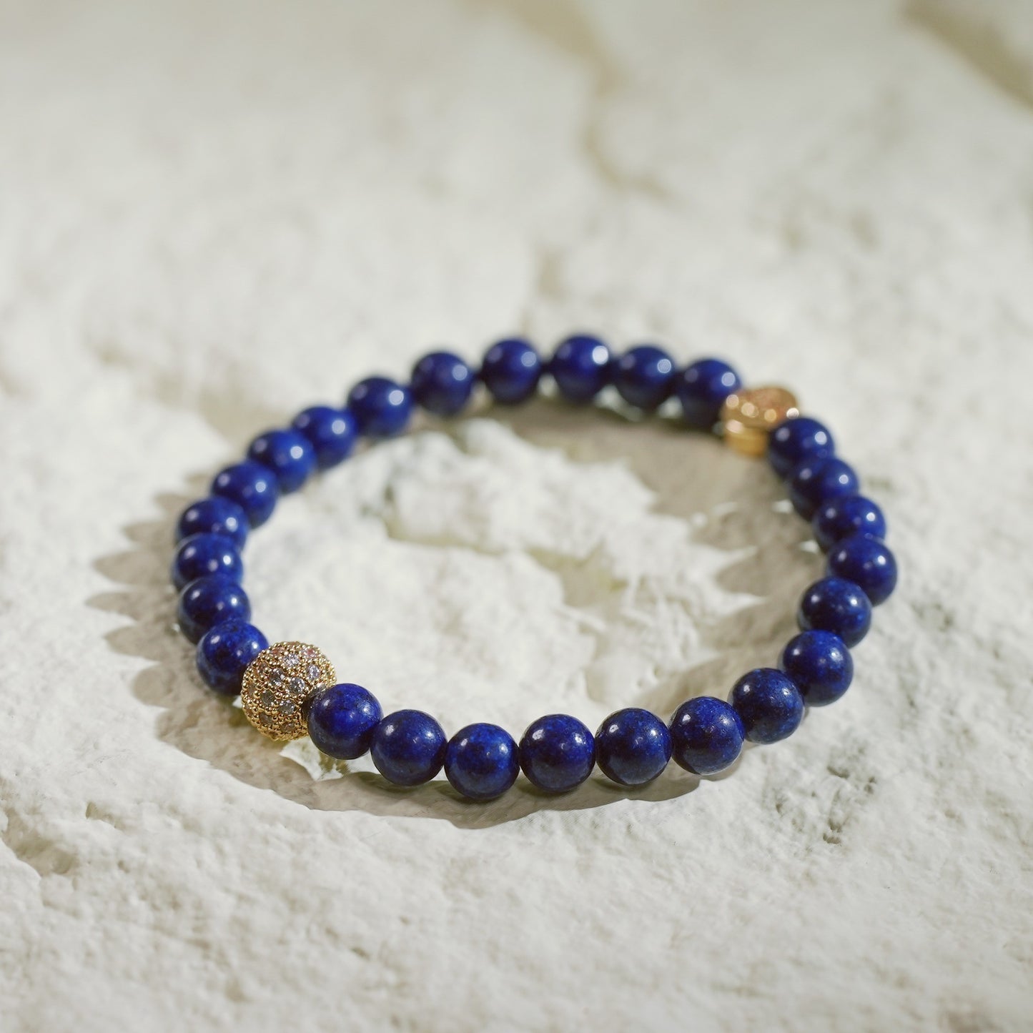 A stretch bracelet made with deep indigo lapis lazuli beads and a silver-plated CZ accent, finished with a GinaKimKR logo tag. Elegant, classic, and grounding.