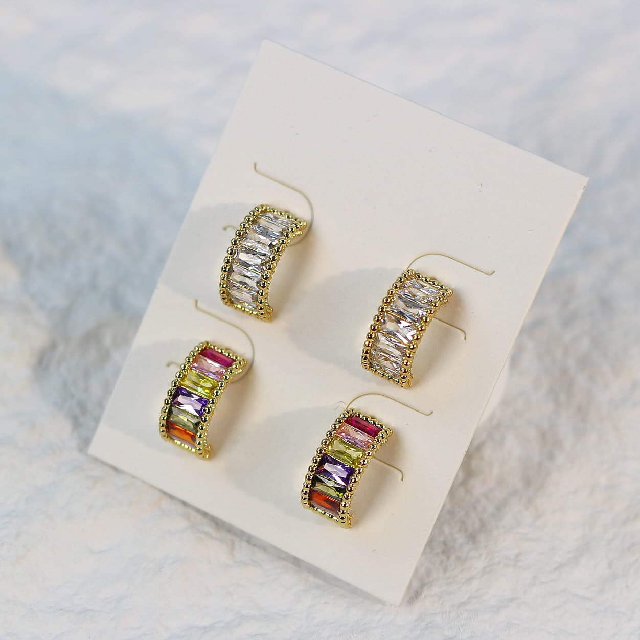 Lumière Arc Earring Set shown with gentle shadows and soft white card background, highlighting the dual crystal styles in gold post earrings.