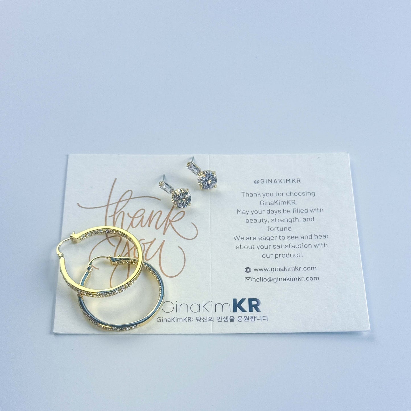 GinaKimKR Luna Spark Earring Set held in hand, emphasizing design contrast between CZ studs and gold hoops