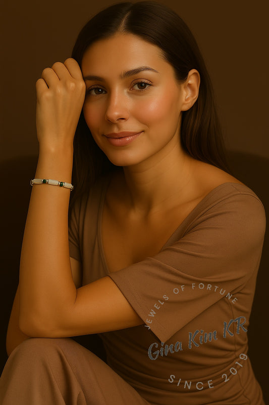 A woman wearing the Lunar Light Stretch Bracelet by GinaKimKR. The soft glow of moonstone and deep green CZ sparkle highlight a modern and luxurious style.
