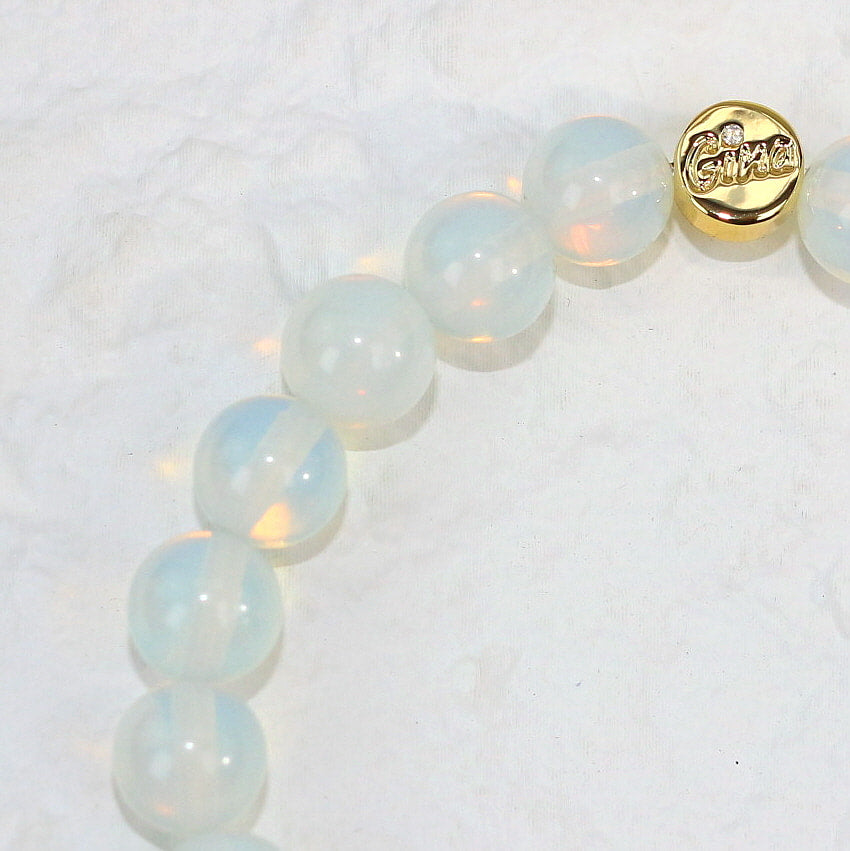 Close-up of Moonstone Strength Bracelet showing the natural variation in 8mm beads and the signature Gina gold tag, highlighting its refined energy.
