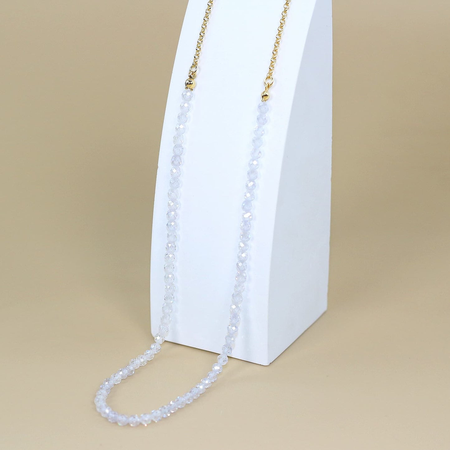 Morning Light Necklace made with clear faceted CZ beads and a gold-plated chain, styled on soft fabric. Features GinaKim logo tag for elegant Korean minimalism.