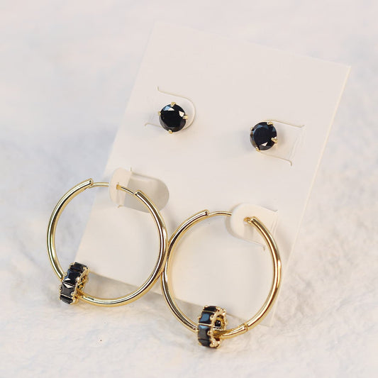 Noir Balance Earring Set displayed on a cream card, featuring 6mm black CZ studs paired with 30mm gold hoops accented by jet black crystals.
