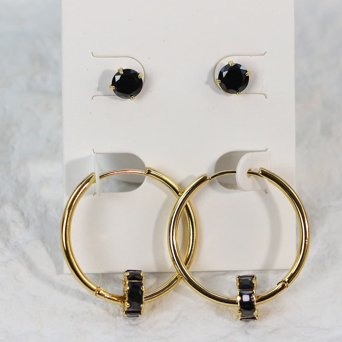 Front-facing image of Noir Balance Earring Set, with symmetric alignment of 6mm black CZ studs and crystal-accented gold hoops on a soft card.