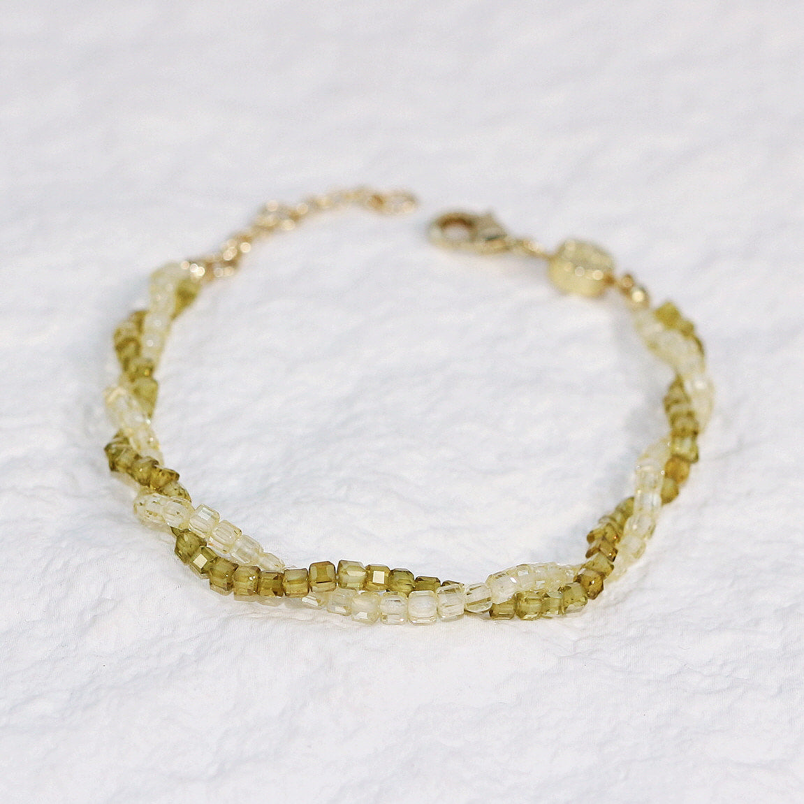Flat-lay image of Olive Prism Bracelet highlighting the soft green CZ beads and subtle shimmer, arranged in a circular shape on a clean white background.