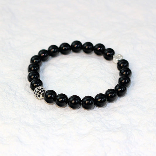 Angled flat-lay view of the Onyx Strength Bracelet with glossy black stones, emphasizing bold elegance and minimalist unisex appeal.