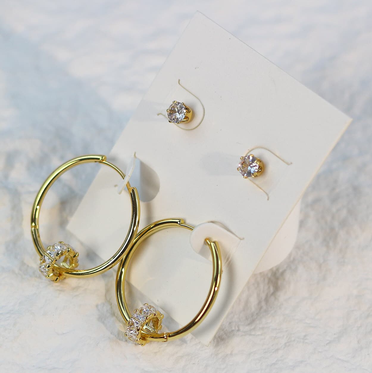 Front-facing product card of Radiant Harmony Earring Set, highlighting the sparkle of crystal-accented gold hoops and cubic zirconia studs.