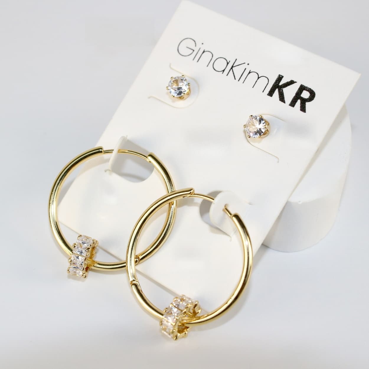 Angled view of Radiant Harmony Earring Set showing gold hoops adorned with crystals and matching 6mm CZ studs on a soft cream card.