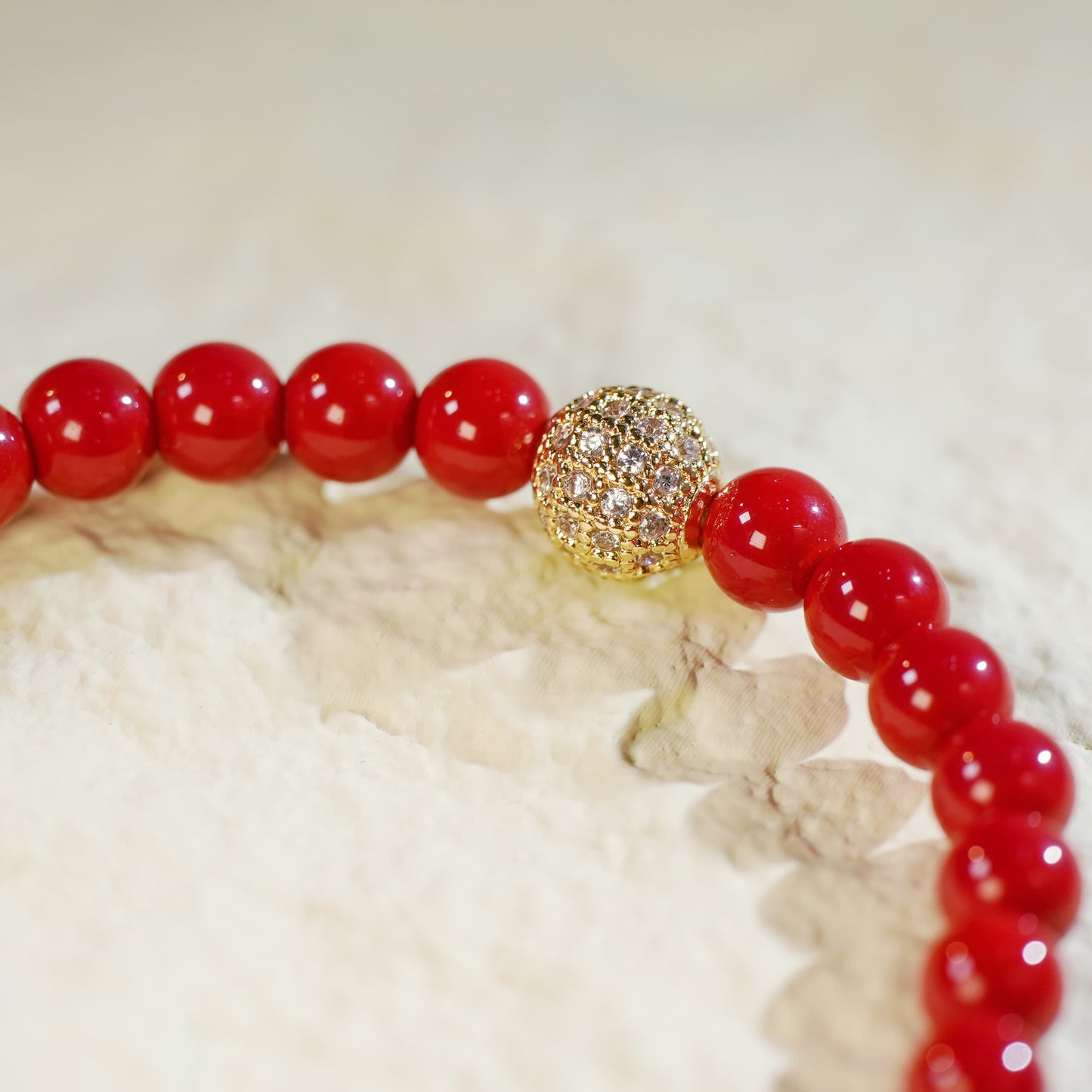 Close-up of the Red Jasper Fortune Bracelet showing rich red beads, gold CZ accent, and signature GinaKimKR charm.