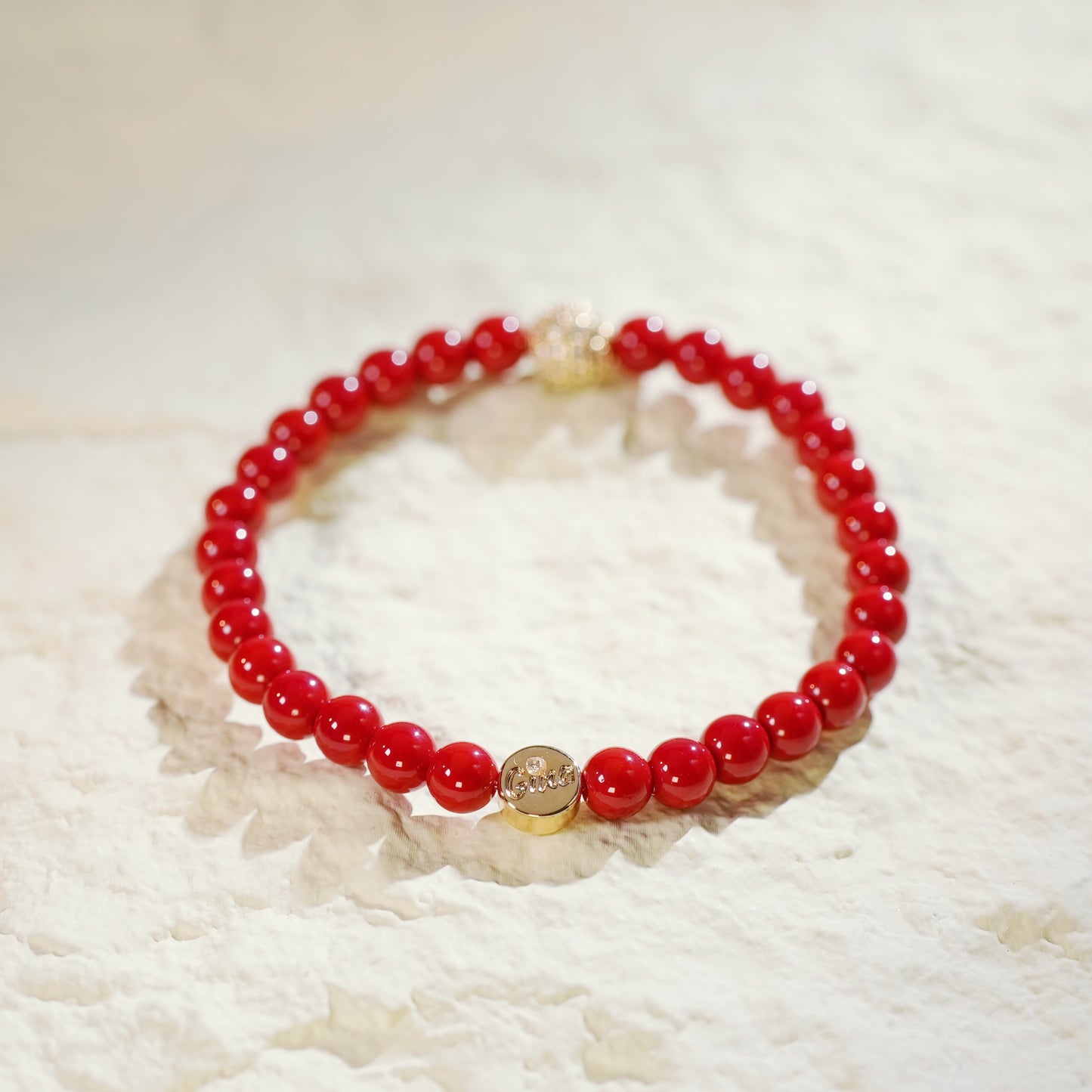 A natural red jasper stretch bracelet with gold-plated CZ bead, worn on the wrist. Designed for grounding and vitality by GinaKimKR.