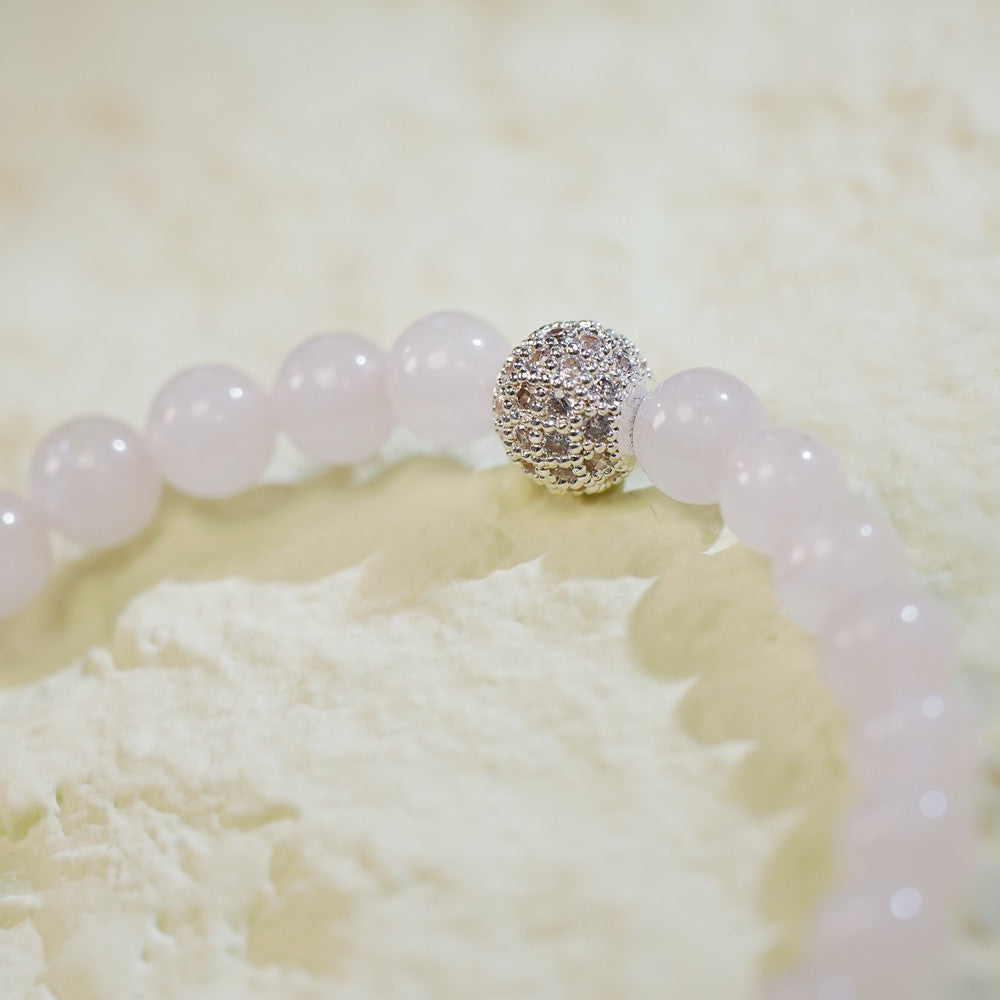 Close-up of the Rose Quartz Fortune Bracelet by GinaKimKR showing natural pink quartz beads, a sparkling CZ accent, and signature charm. Romantic and refined.