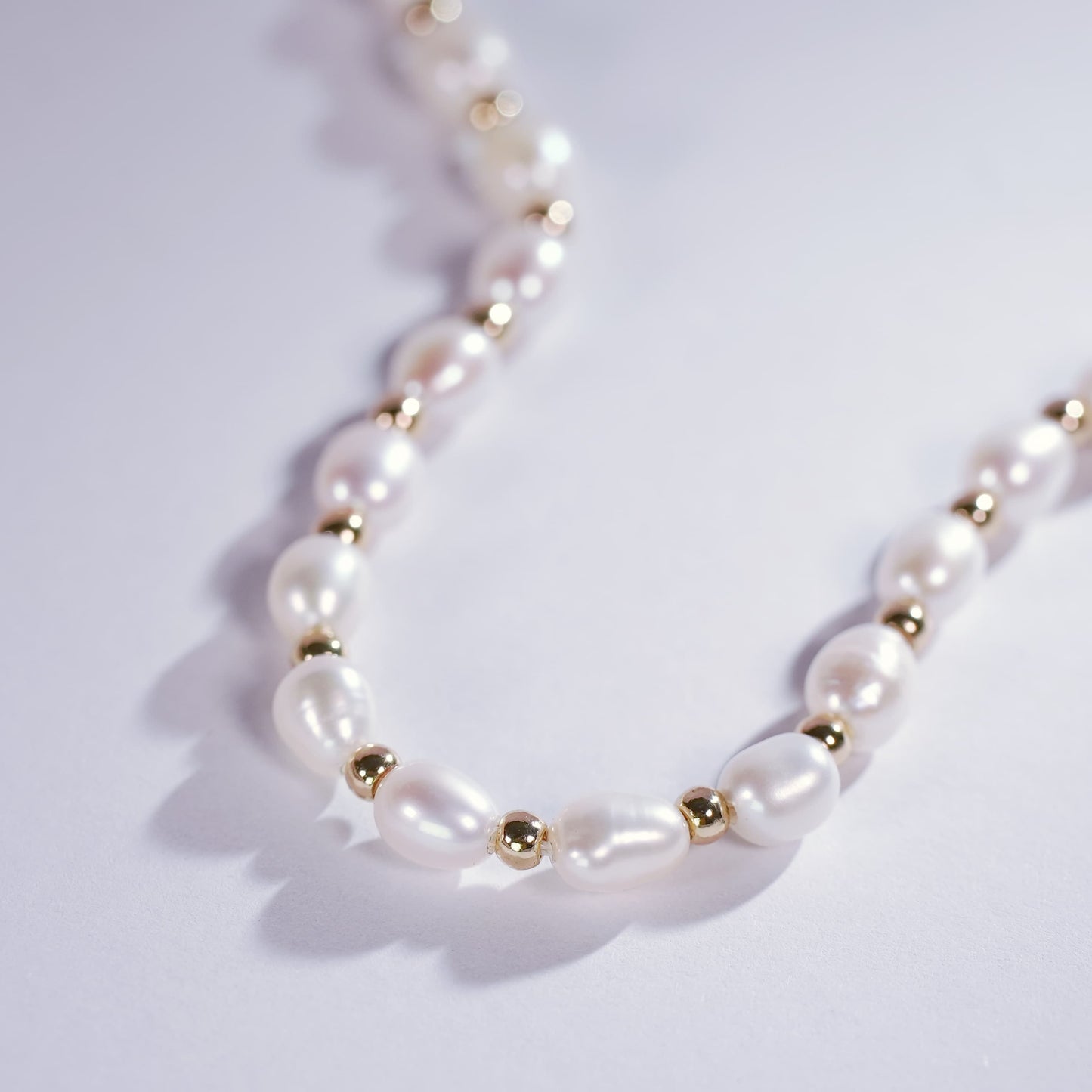 Close-up of the Serenity Pearl Necklace with smooth, oval freshwater pearls and gold accents, showcasing timeless elegance and fine craftsmanship.