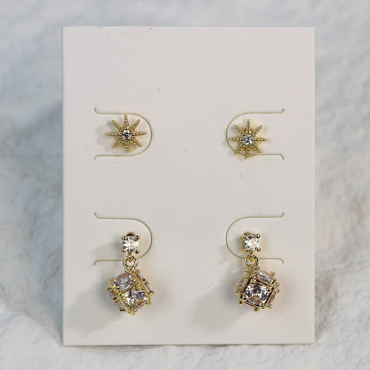 Close-up of Starlume gold star-shaped CZ studs and six-sided drop earrings with round crystals.